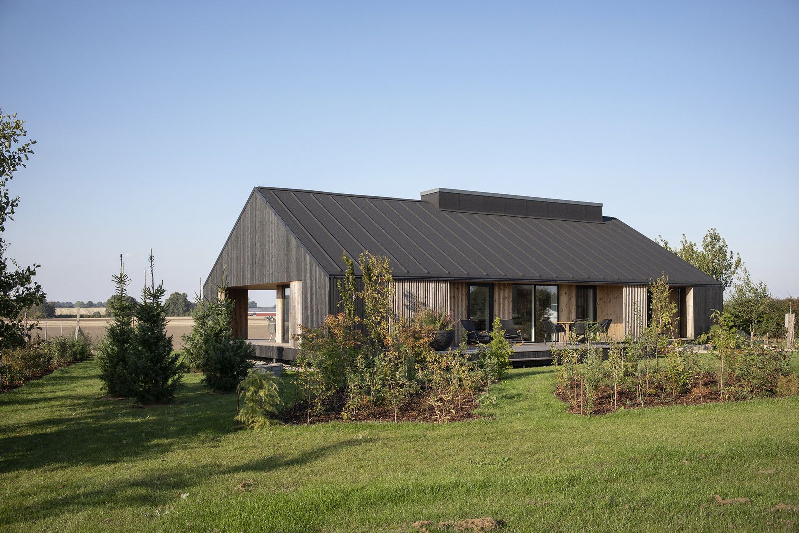 Moderne hus med trælameller, sort tag og terrasse